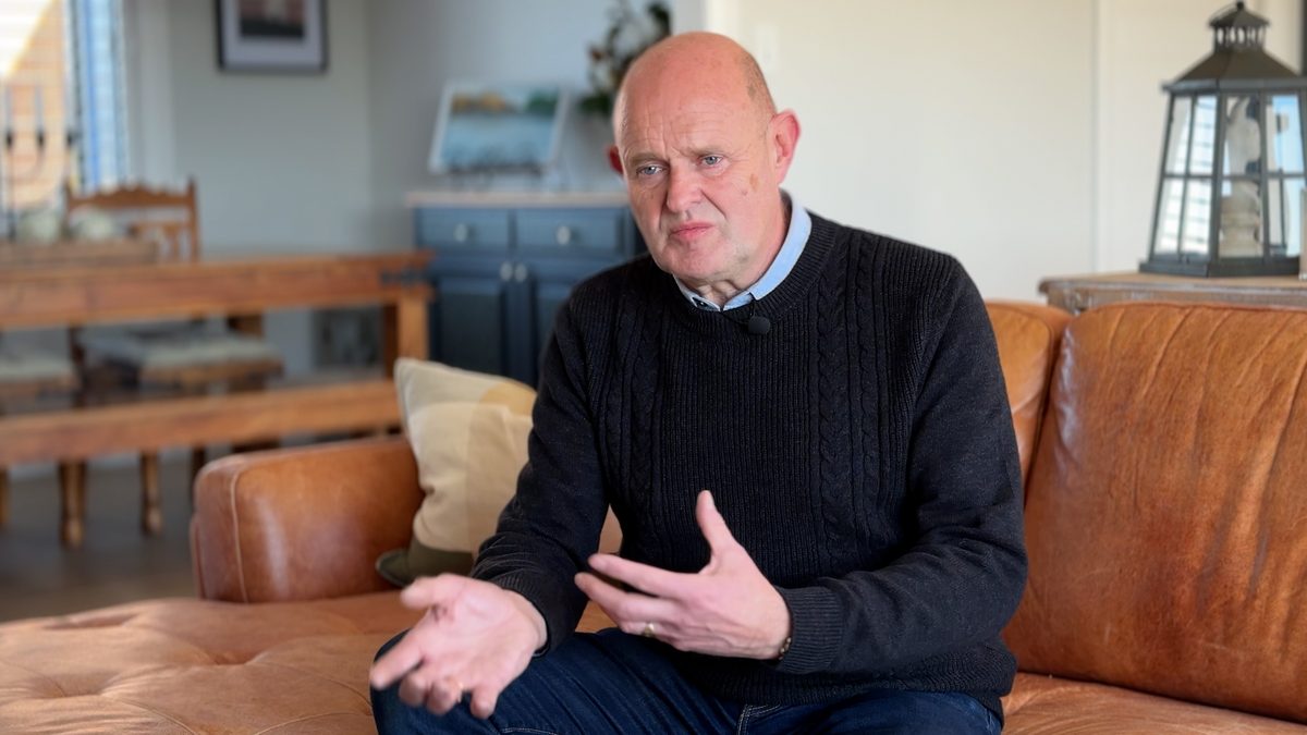 Jeff Wilson on the couch at home in Canterbury, mid-sentence, hands explaining