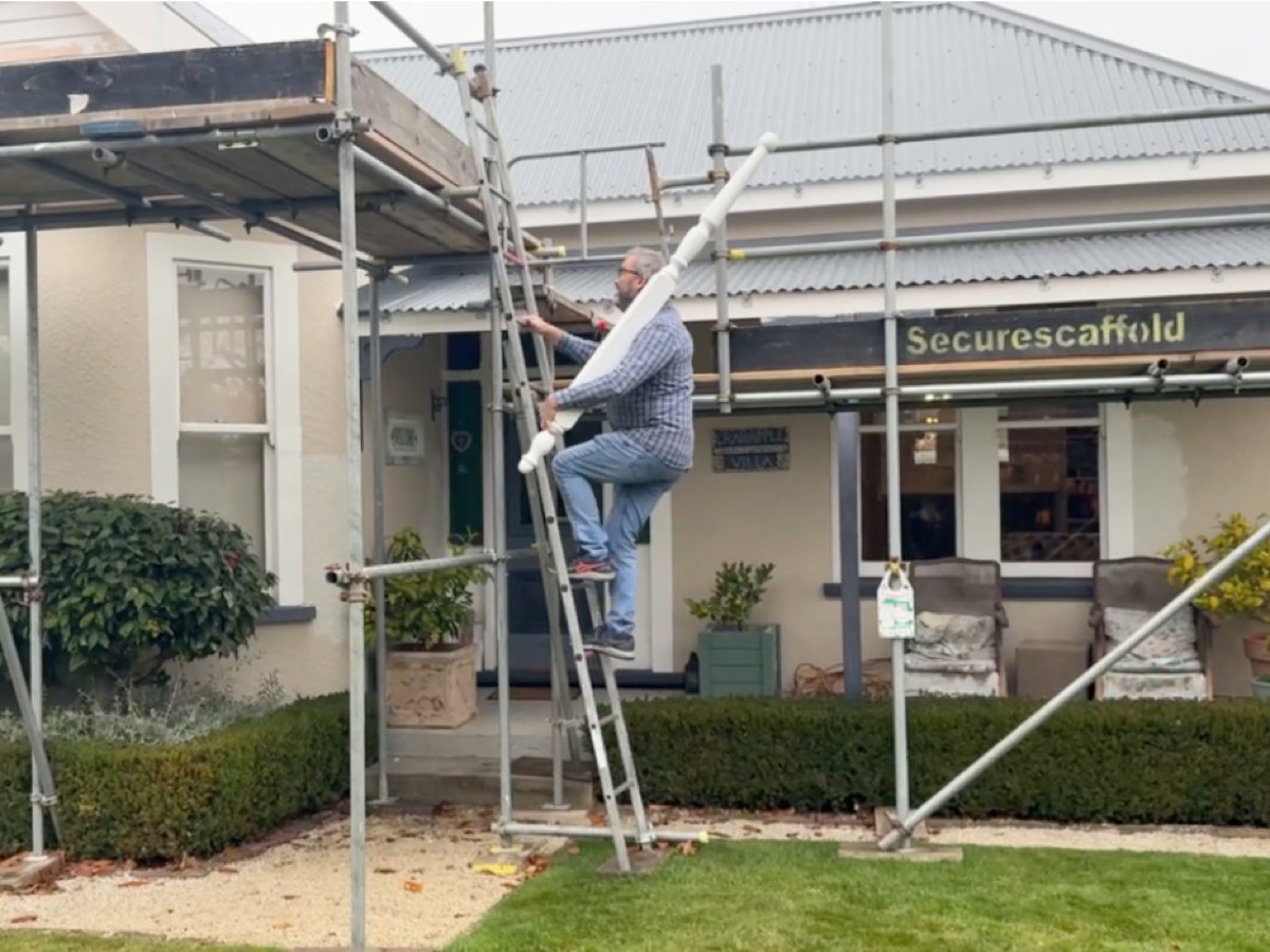 Johnnie climbing a scaffold ladder against his villa during the re-roof