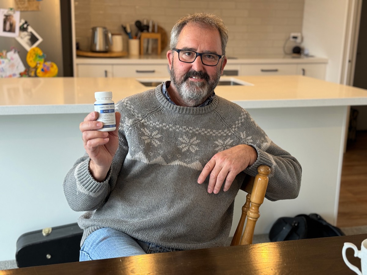 Johnnie holding a bottle of Koru Joint at his kitchen bench